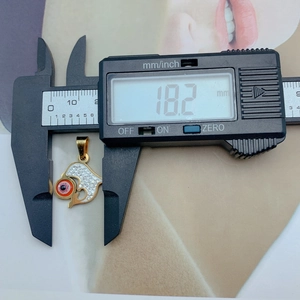 Macro view of golden dolphin pendant with evil eye showing 18.2mm width on digital caliper