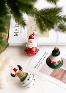 Close-up of red Santa Claus metal bell ornament with pine branch holiday background