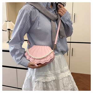 Detail of pink shell crossbody bag featuring pearl handle and vertical texture design