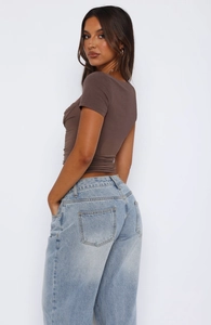 Detail of slim-fit ruched short-sleeve top in brown with casual jeans on white background