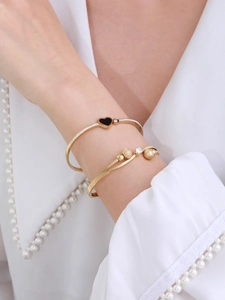 Detail of elegant gold-toned heart and butterfly bracelets on model's wrist