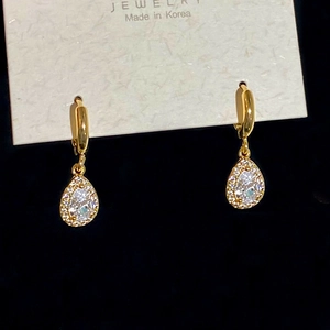 Detailed macro view of 18K gold drop earrings with pear-cut zircon and pave crystals