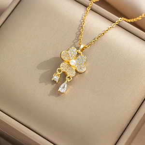 Elegant gold necklace with pearl and zircon clover pendant in a beige leather jewelry box