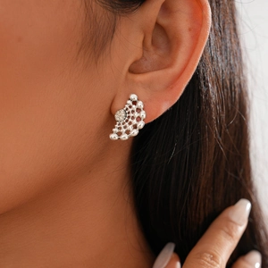 Détail de boucles d'oreilles argentées ajourées avec strass portées par un mannequin