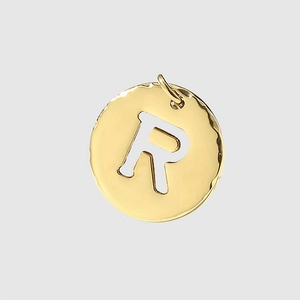 Macro detail of a gold stainless steel letter R pendant charm with circular frame