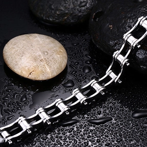Macro shot of silver stainless steel chain bracelet on wet black pebbles with water drops