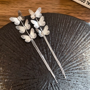Macro shot of silver butterfly tassel earrings with zircon details on black tray