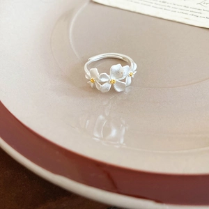 Detailed macro of adjustable silver flower ring with yellow stamens on ceramic plate