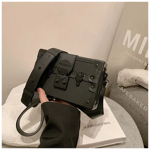 Detail of black box shoulder bag with metallic rivets and mechanical press lock closure