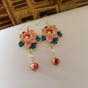 Nahaufnahme der rosa Emaille-Blumenohrringe mit Perlen und goldenen Akzenten