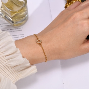 Detail of 18K gold bracelet with micro-pave zircon circle charm on a fashion magazine
