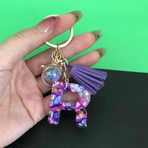 Detailed close-up of resin letter P keychain with purple tassel and gold metal hardware