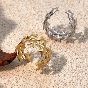 Minimalist gold and silver star cutout open rings displayed on a natural sand background