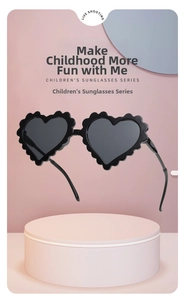 Detail of heart-shaped kids sunglasses with trendy wavy edges on pink pedestal