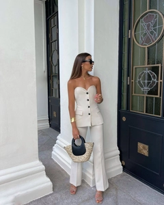 Detail shot of cream two-piece set featuring black buttons and side pocket flaps