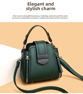 Detail of dark green leather handbag featuring a matte black clasp and side zippers
