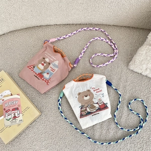 Détail de broderie d'ours et bandoulières tressées sur mini sacs en toile Oxford