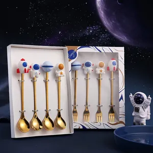 Golden space themed dessert spoon and fork set with astronaut and rocket figurines