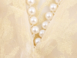 Detailed macro shot of white pearls and golden lace fabric with luxury texture