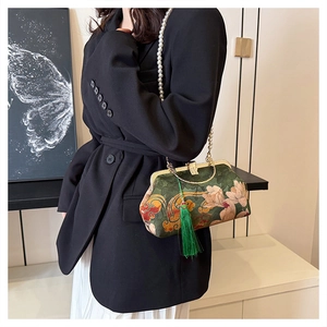 Detail of vintage floral green handbag with pearl strap and tassel on black blazer