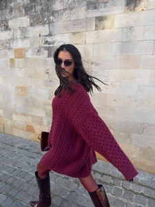 Deep red oversized cable-knit sweater for women styled with knee-high boots