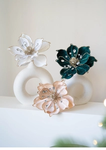Detailed view of velvet magnolia flowers with glitter edges and rhinestones in white vases