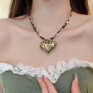 Close-up of leopard print heart pendant necklace on model's neck with gold alloy accents