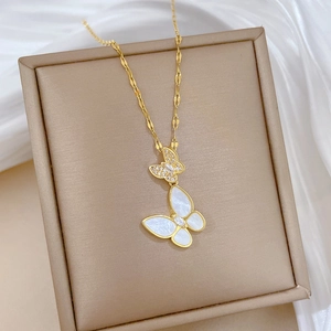 Close-up of titanium steel gold butterfly pendant with white shell and micro-inlaid stones