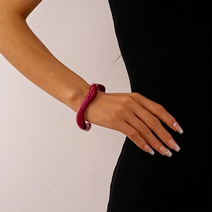Detail of wavy resin cuff bracelet in deep burgundy with a glossy polished finish