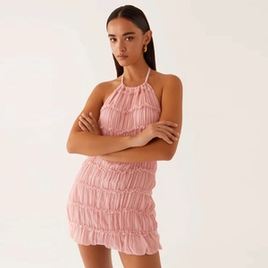 Detail of pink halter neck mini dress featuring tiered ruffles and pleated chiffon fabric