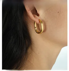 Close-up of elegant gold U-shaped chunky hoop earrings worn on a model's ear