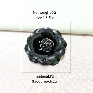 Detail view of a black PU leather camellia flower brooch with silver metal stamen details