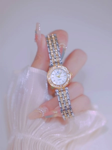 Close-up of a silver and gold quartz watch with rhinestones on a female wrist