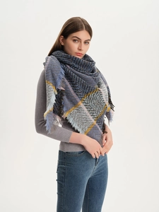 Detail of soft plaid scarf featuring navy and yellow tartan pattern with fringe edges