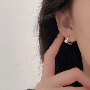 Close-up of elegant gold pearl olive stud earrings worn by a model in profile view