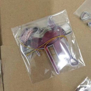 Detail view of a western saddle acrylic pendant in protective packaging on cardboard
