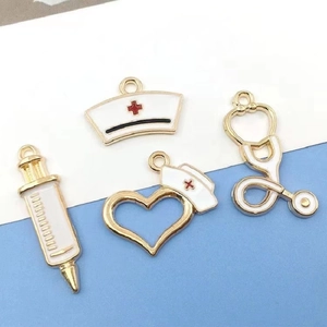 Close-up of gold medical charms with white enamel nurse cap, syringe and stethoscope