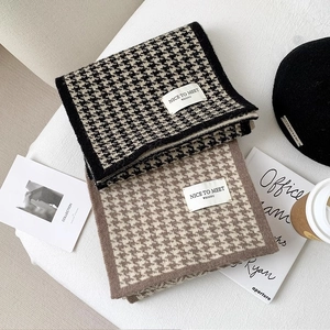 Close-up of thick knitted houndstooth scarves with premium texture and woven brand label