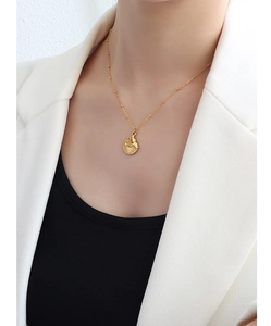 Close-up of a 18k gold fishtail circular pendant necklace worn by a fashion model