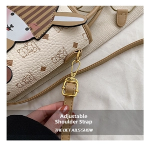 Detail of adjustable khaki leather strap with gold hardware on a cream bear bucket bag