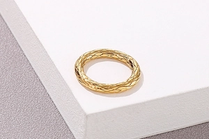 Nahaufnahme eines goldenen Rings mit gestepptem Rautenmuster und poliertem Diamant-Gitter