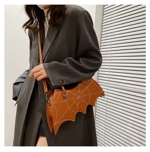 Detailed close-up of brown bat-shaped crossbody bag with white spider web stitching