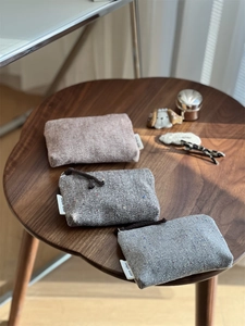 Three mini herringbone tweed pouches with colorful flecks and a side logo tag detail