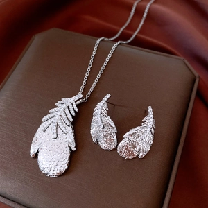 Silver feather jewelry set with necklace and earrings on a brown gift box with silk fabric