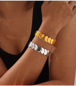 Detailed shot of layered gold and silver heart-link titanium steel bracelets on model