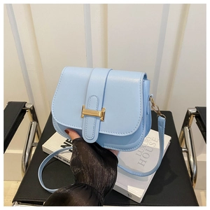 Close-up of light blue leather square bag featuring a prominent golden H-shaped clasp