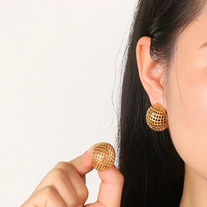 Moderne goldene hohle Gitterkugel-Ohrringe getragen von einem Model im minimalistischen Stil