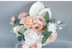 Close-up of artificial bridal bouquet with peach roses, pearls, and frayed ribbon decor
