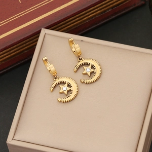 Elegant gold moon and star hoop earrings with clear crystal on a vintage book backdrop