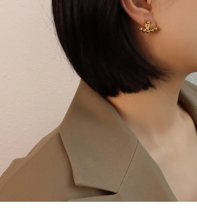 Close-up of a model wearing golden spherical titanium steel earrings in a modern style
